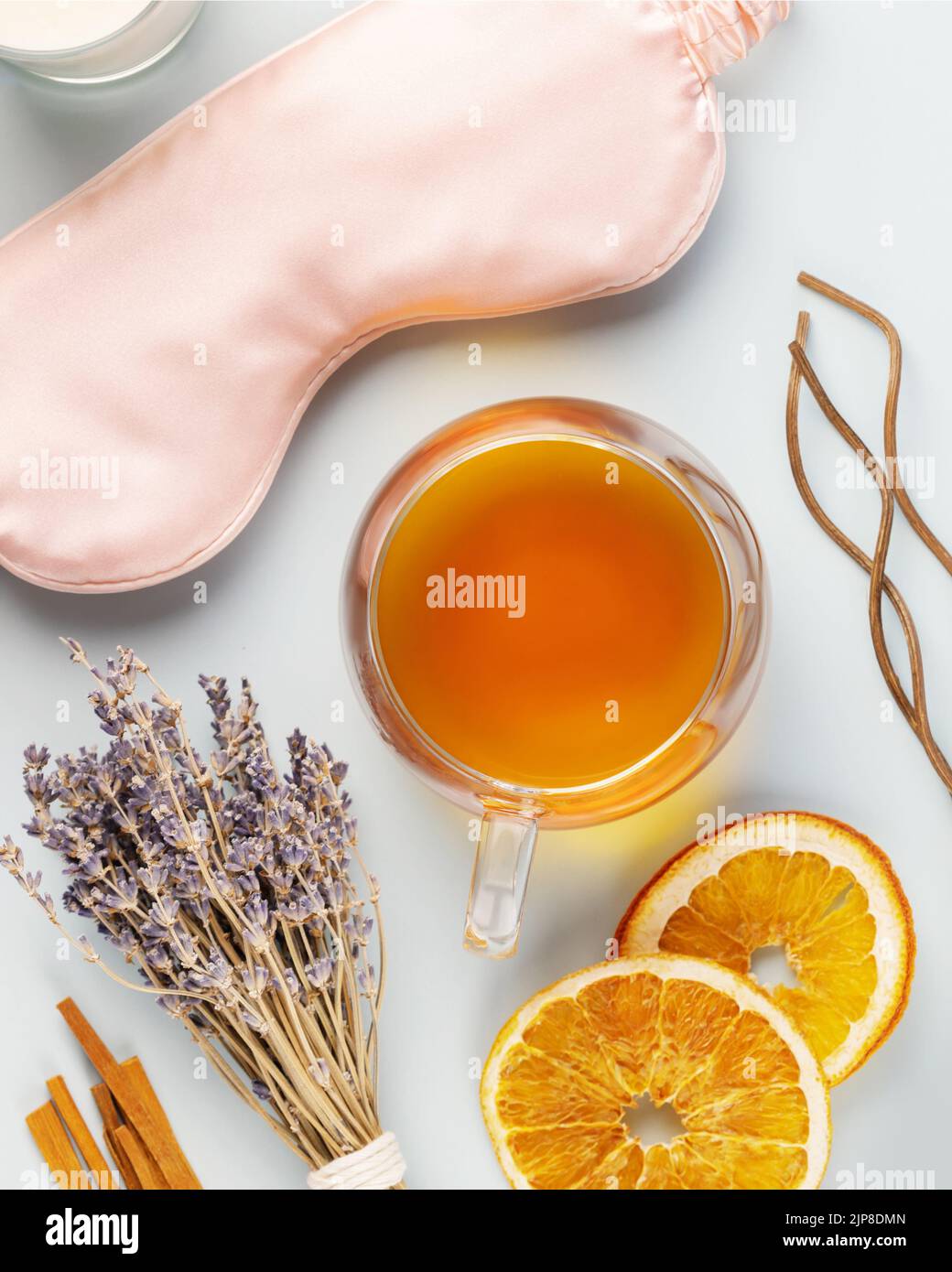 Self-care flat lay with sleeping mask, lavender flower, herbal tea, dry oranges and aroma sticks on a blue background. Concept of Me time and no depre Stock Photo