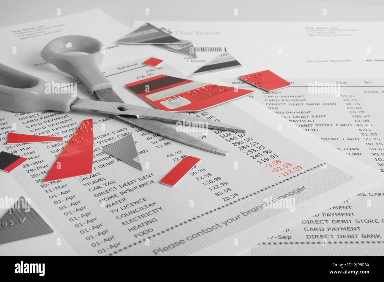 Cut up Credit Card and a pair Scissors on top of a Bank Statement showing debt Stock Photo
