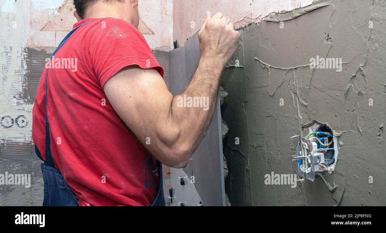 Laying wall ceramic tile. Renovating the wall. Construction worker