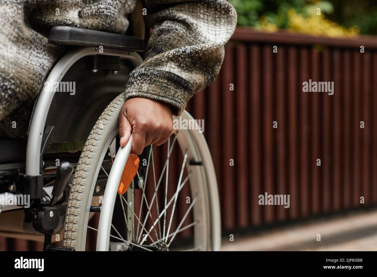 Close up of unrecognizable black woman with disability pushing wheelchair wheel, copy space Stock Photo