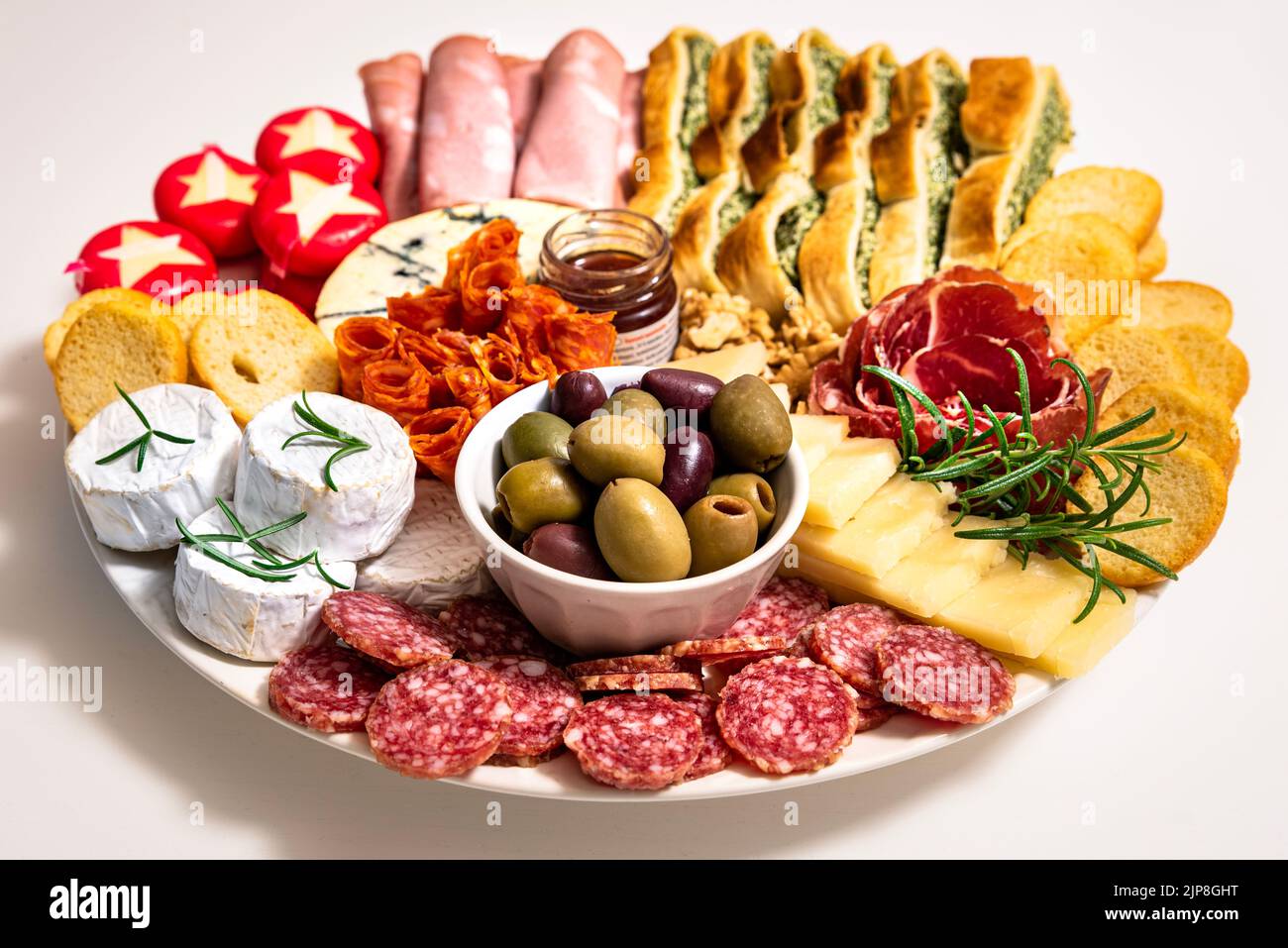 Lunch meal or appetiser with a single dish of salami, pepperoni, brie cheese, ham. Dinner plate or appetizer with salumi, cheeses and focaccia bread Stock Photo