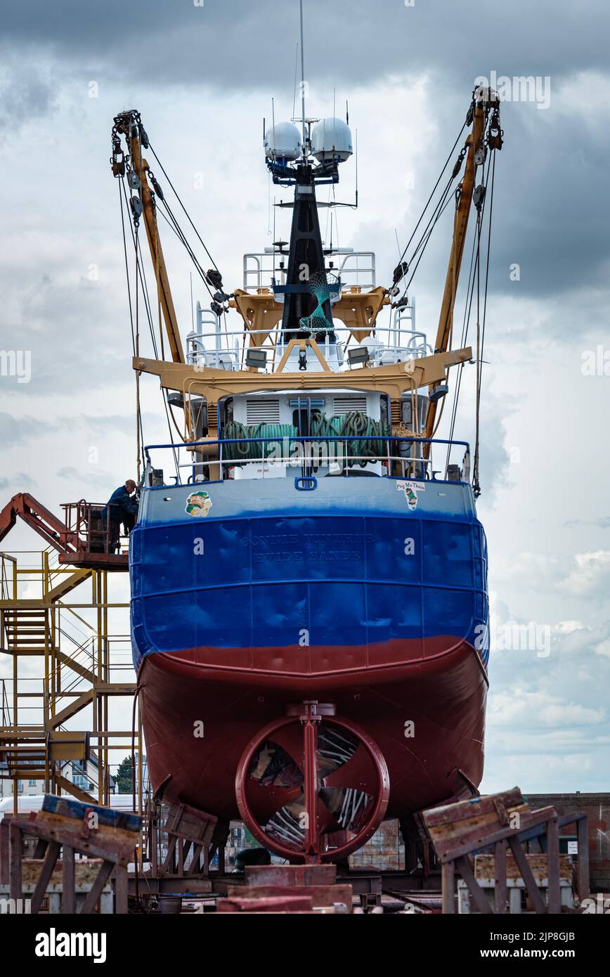 Stern of vessel or ship with visible propeller and ropes being repaired in dock. Back view of docked fishing trawler with mechanical problems in port Stock Photo
