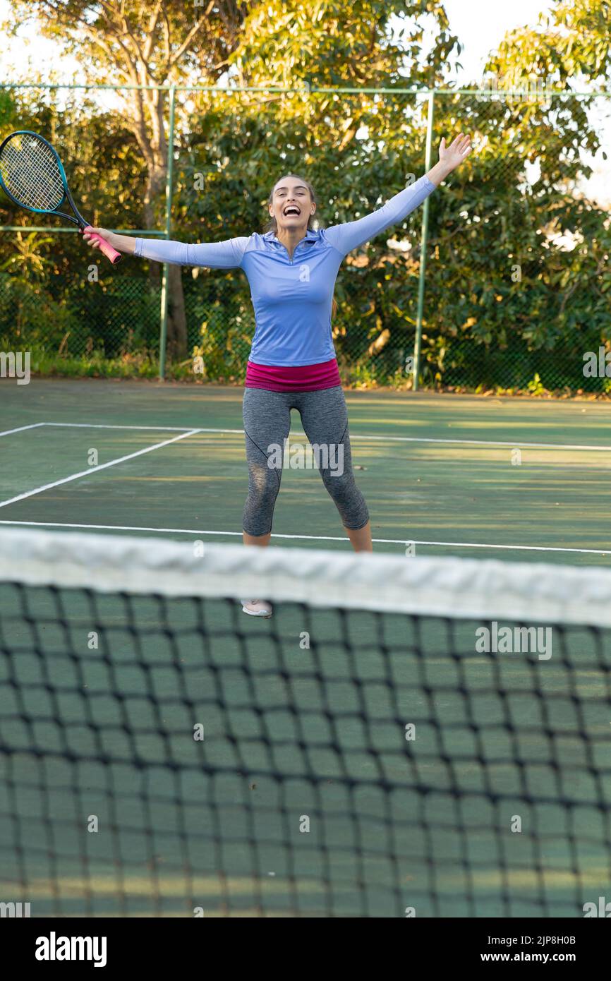 Happy caucasian woman playing tennis celebrating on outdoor tennis court Stock Photo