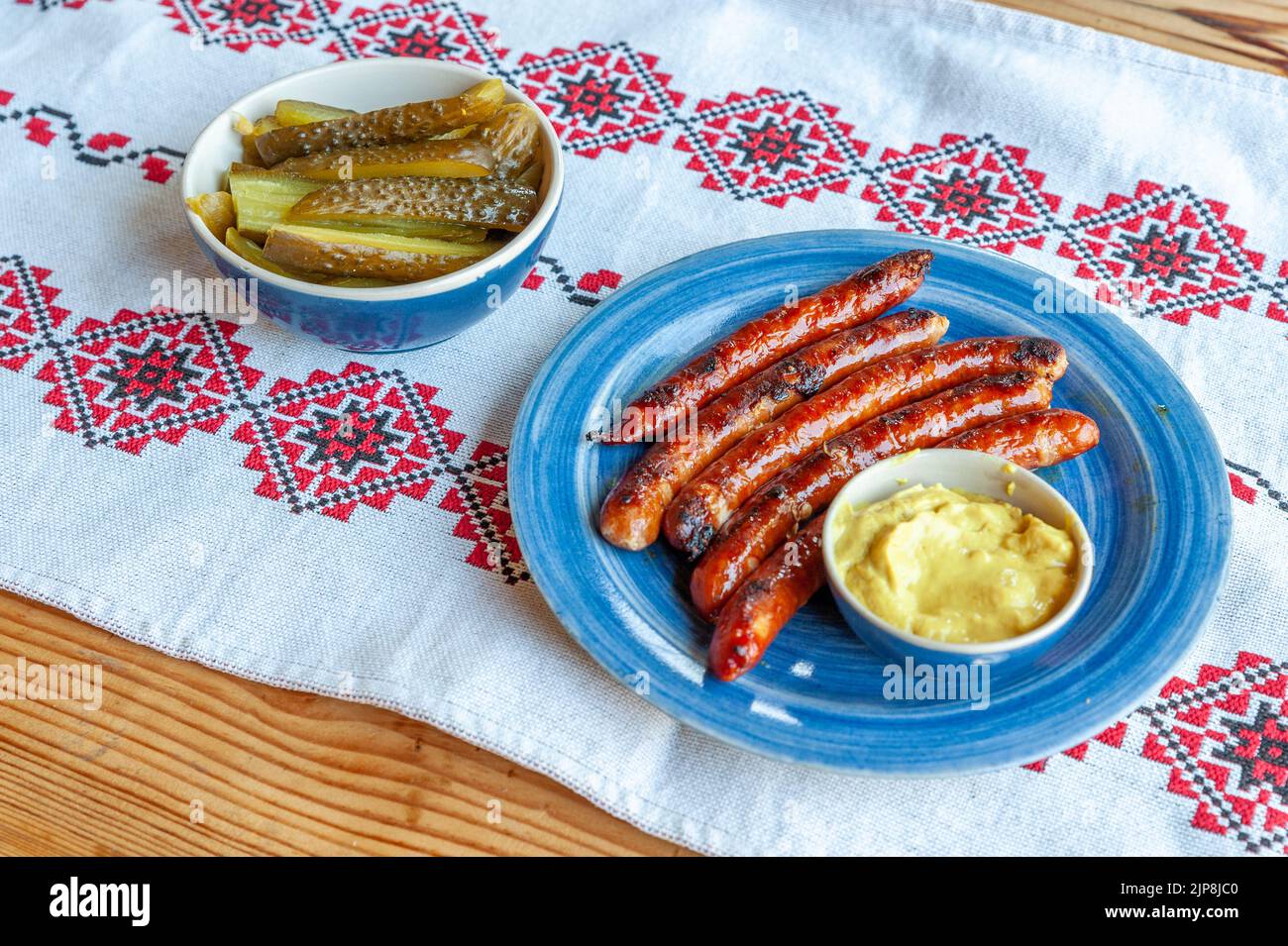delicious dish with grilled sausages, pickled cucumbers and mustard Stock Photo