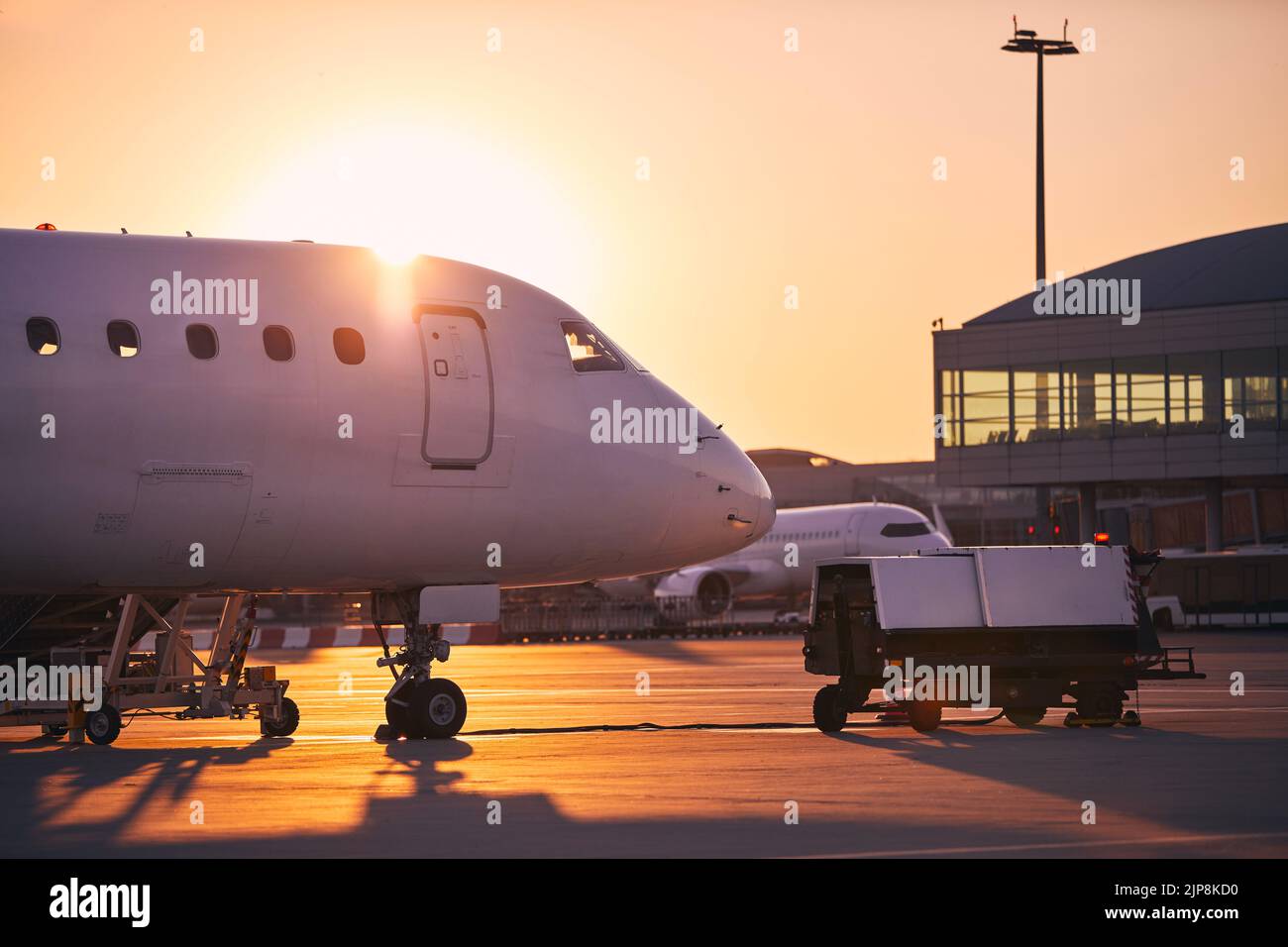 Preparation of airplanes before flight. Airport at golden sunrise. Stock Photo