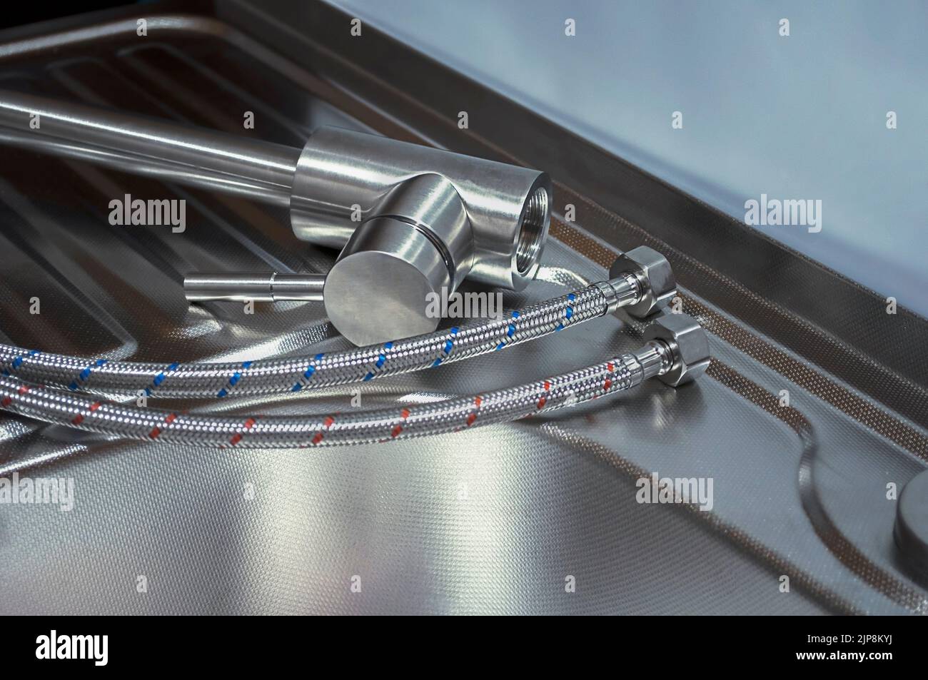 Installation of the kitchen faucet to a sink. A kitchen faucet is fitted with hoses for