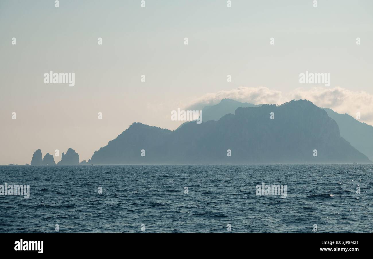 Capri faraglioni Wave erosion rock formations seascape of the island of Capri Italy in the bay of Naples seen in the sea mist with pleasure boats. Stock Photo