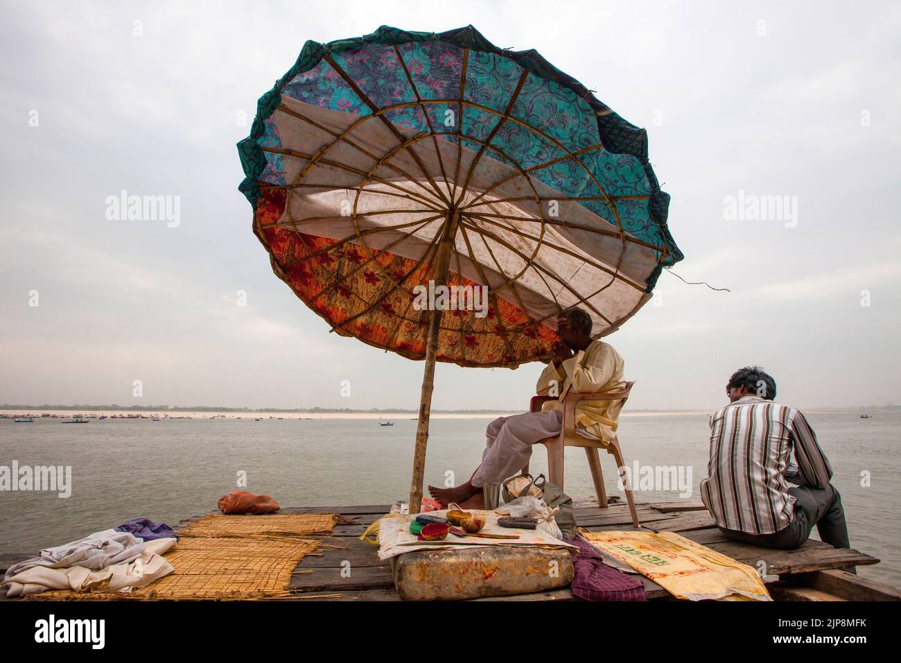 Priest sitting below huge umbrella at Dashashwamedh Ghat on Ganga river Ganges, Varanasi, Banaras, Benaras, Kashi, Uttar Pradesh, India Stock Photo