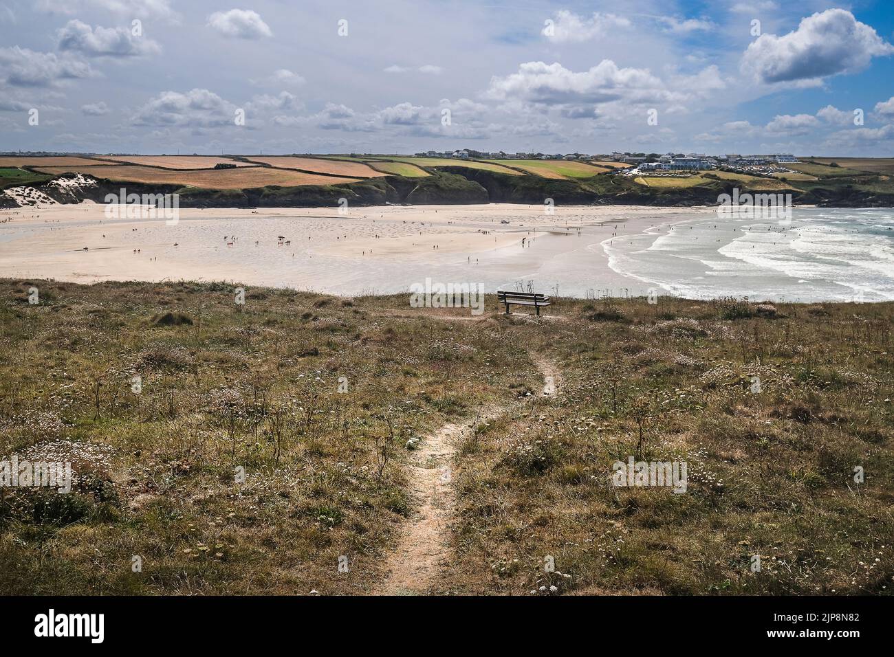 A rough footpathgn leading to a bench on Pentire Point East overlooking low tide at Crantock Beach on the coast at Newquay in Cornwall in the UK. Stock Photo