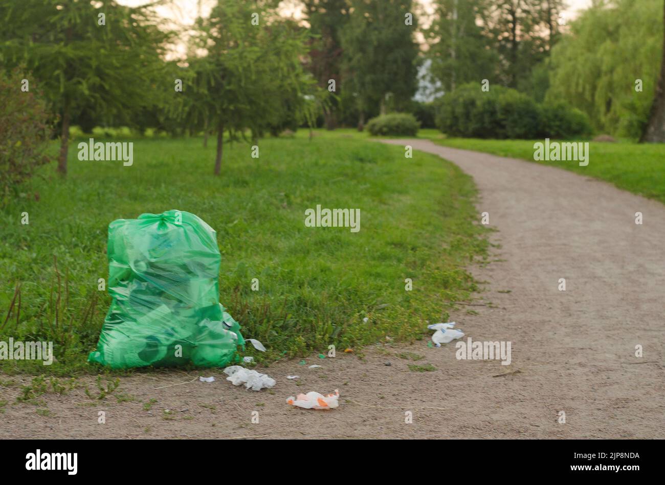 At sunset, a large bag of garbage and scattered garbage in the park Stock Photo Alamy