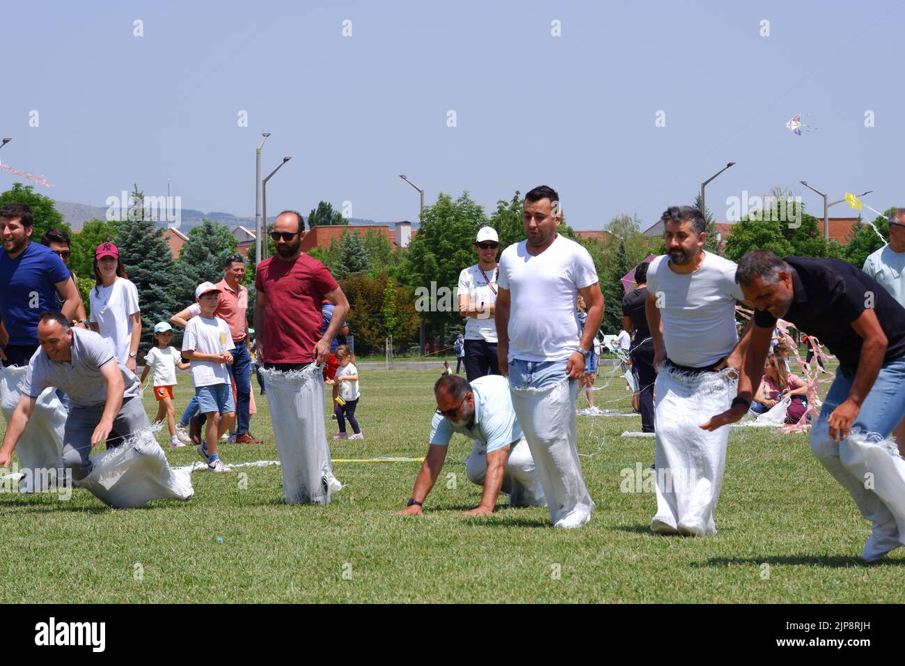 Middle aged People and kids having fun at gunnysack race in summer outdoor Stock Photo