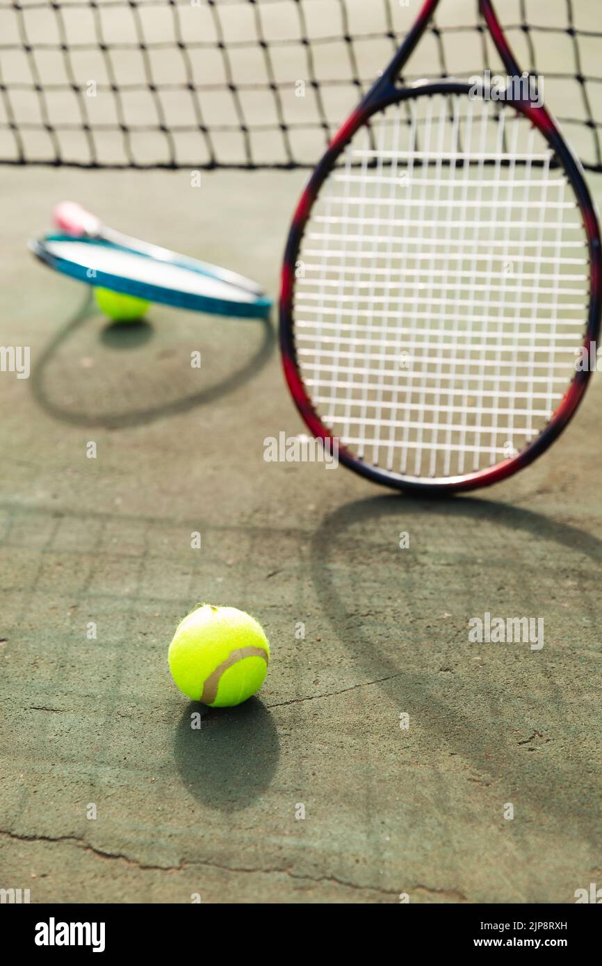 Detail of two tennis rackets and balls by the net at an outdoor tennis