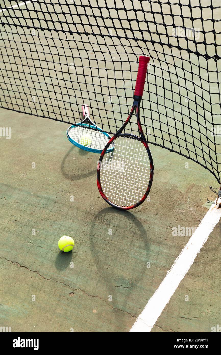 Detail of two tennis rackets and balls by the net at an outdoor tennis