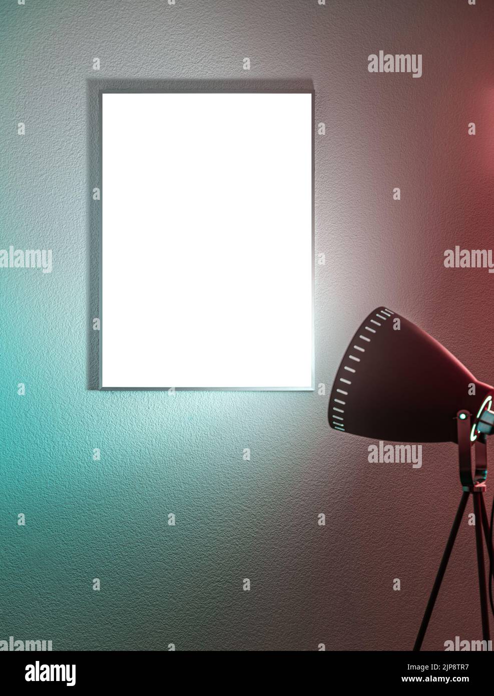 Blank vertical poster in a frame on the wall illuminated by a tripod floor lamp Stock Photo