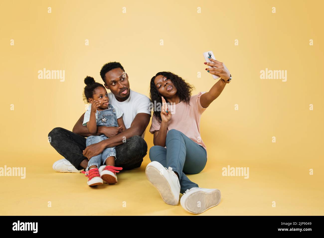 Portrait of smiling african american family of three sitting on floor ...