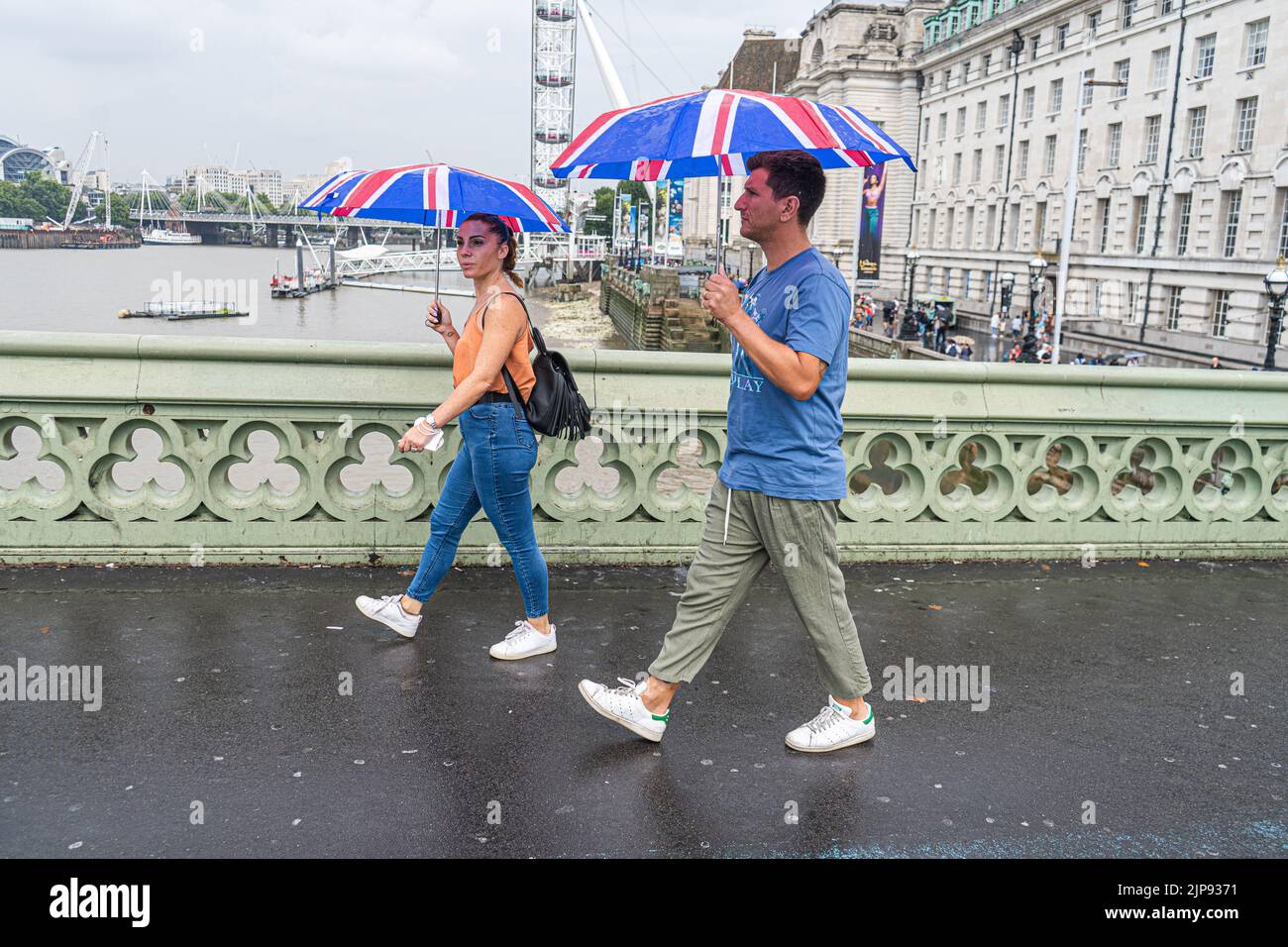 Westminster London, UK. 16 August 2022 . Pedestrian walk with matching Union Jack umbrellas on Westminster bridge during rain showers as the drought ends  after the prolonged dry spell and the driest summer in 46 years as the met office issues a yellow warning for thunderstorms and flash floods . Credit. amer ghazzal/Alamy Live News Stock Photo