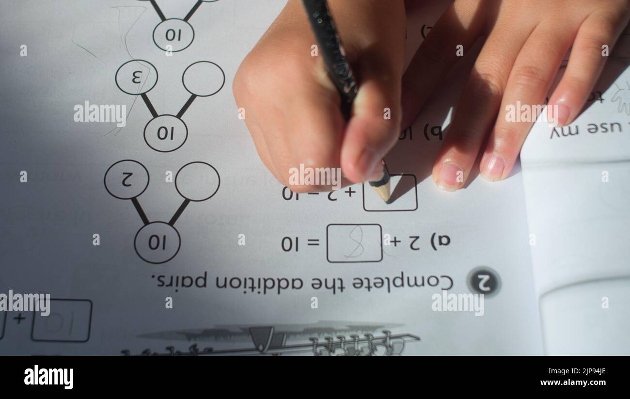 A closeup shot of a child doing their maths homework on a workbook Stock Photo