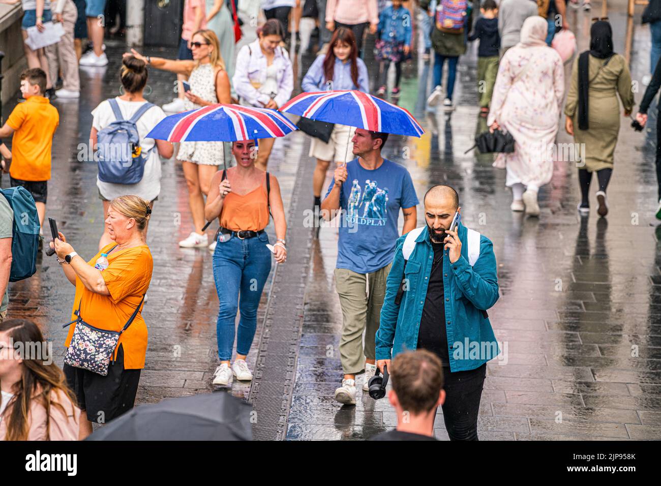 Westminster London, UK. 16 August 2022 . Pedestrians shletering underneath union jack umbrellas on on the southbank during rain showers as the drought ends  after the prolonged dry spell and the driest summer in 46 years as the met office issues a yellow warning for thunderstorms and flash floods . Credit. amer ghazzal/Alamy Live News Stock Photo