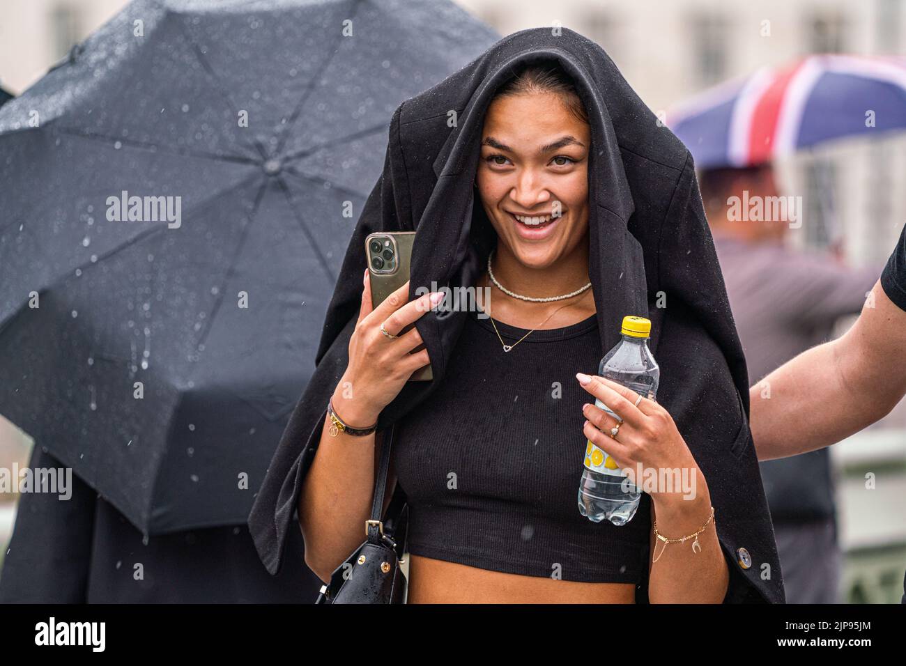 Westminster London, UK. 16 August 2022 . A pedestrian covers her head with a jacket  on Westminster bridge  during rain showers as the drought ends  after the prolonged dry spell and the driest summer in 46 years as the met office issues a yellow warning for thunderstorms and flash floods . Credit. amer ghazzal/Alamy Live News Stock Photo