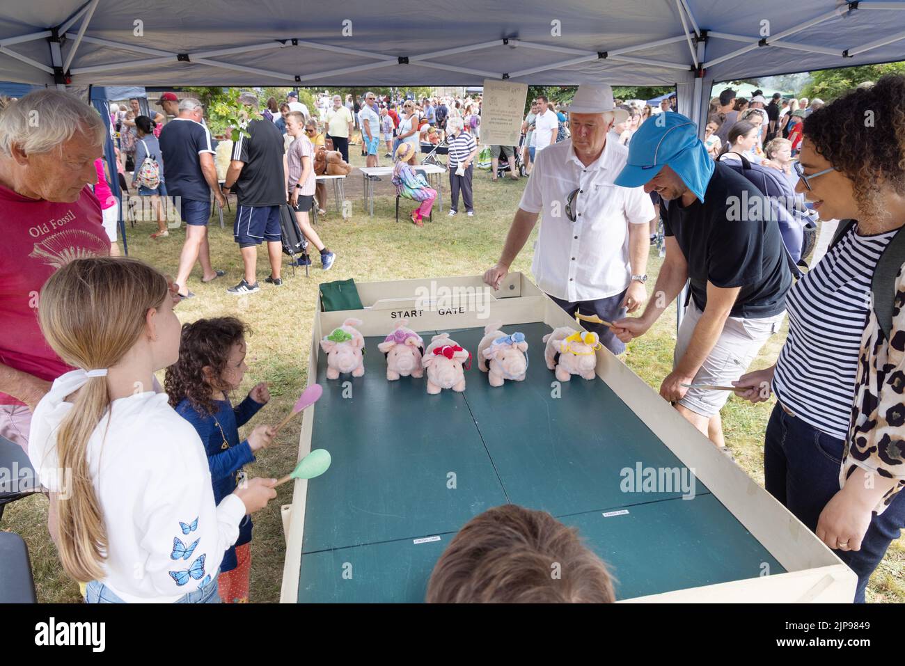 Village fete UK - children playing a game of Pig Race with battery operated pigs; Burton Bradstock village fete, Dorset UK Stock Photo