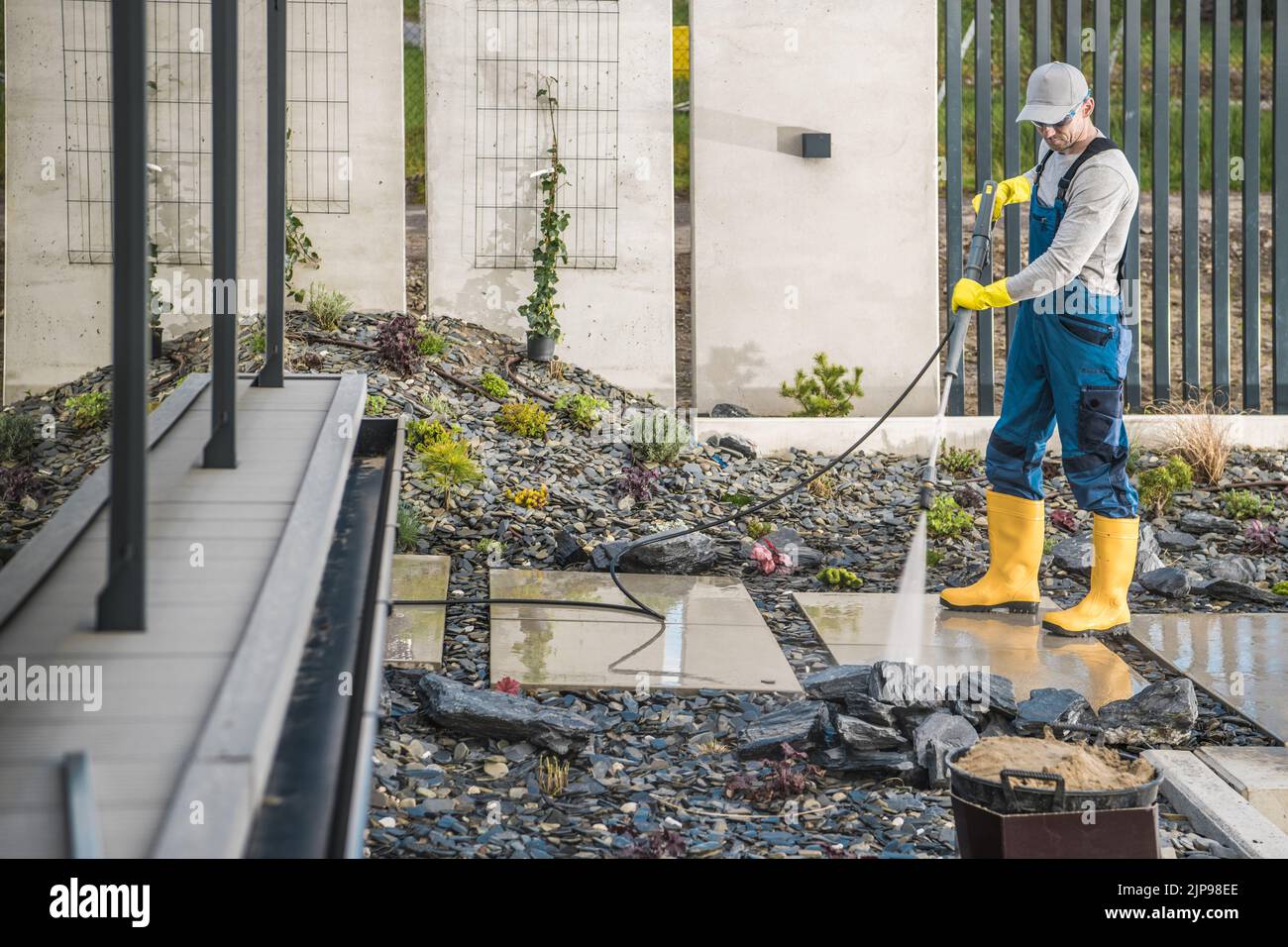 Caucasian Middle Aged Man in Work Clothing and Rubber Boots Cleaning