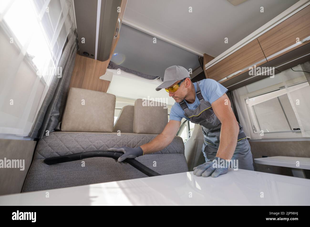 Caucasian Middle Aged Man Cleaning the Interior of Camper Van Vacuuming