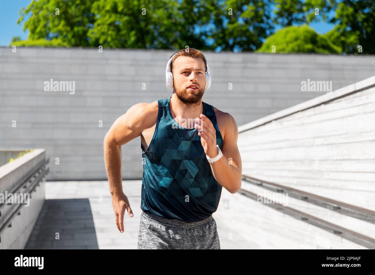 young man in headphones running outdoors Stock Photo