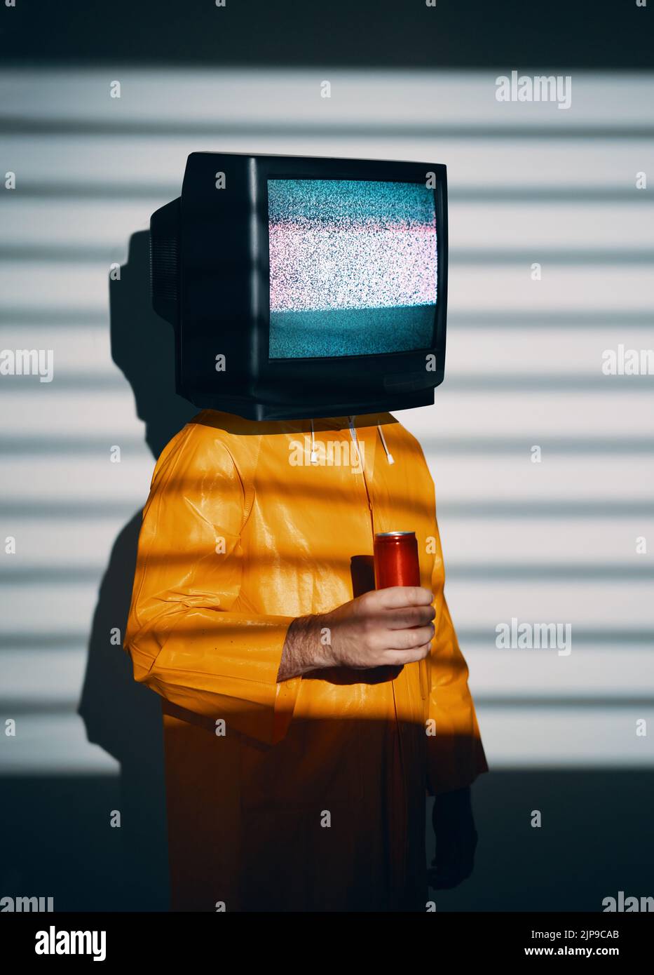 Surreal art of TV addicted man with television instead of head. Media zombie concept with male in bright yellow raincoat holding sweet soda in a red c Stock Photo