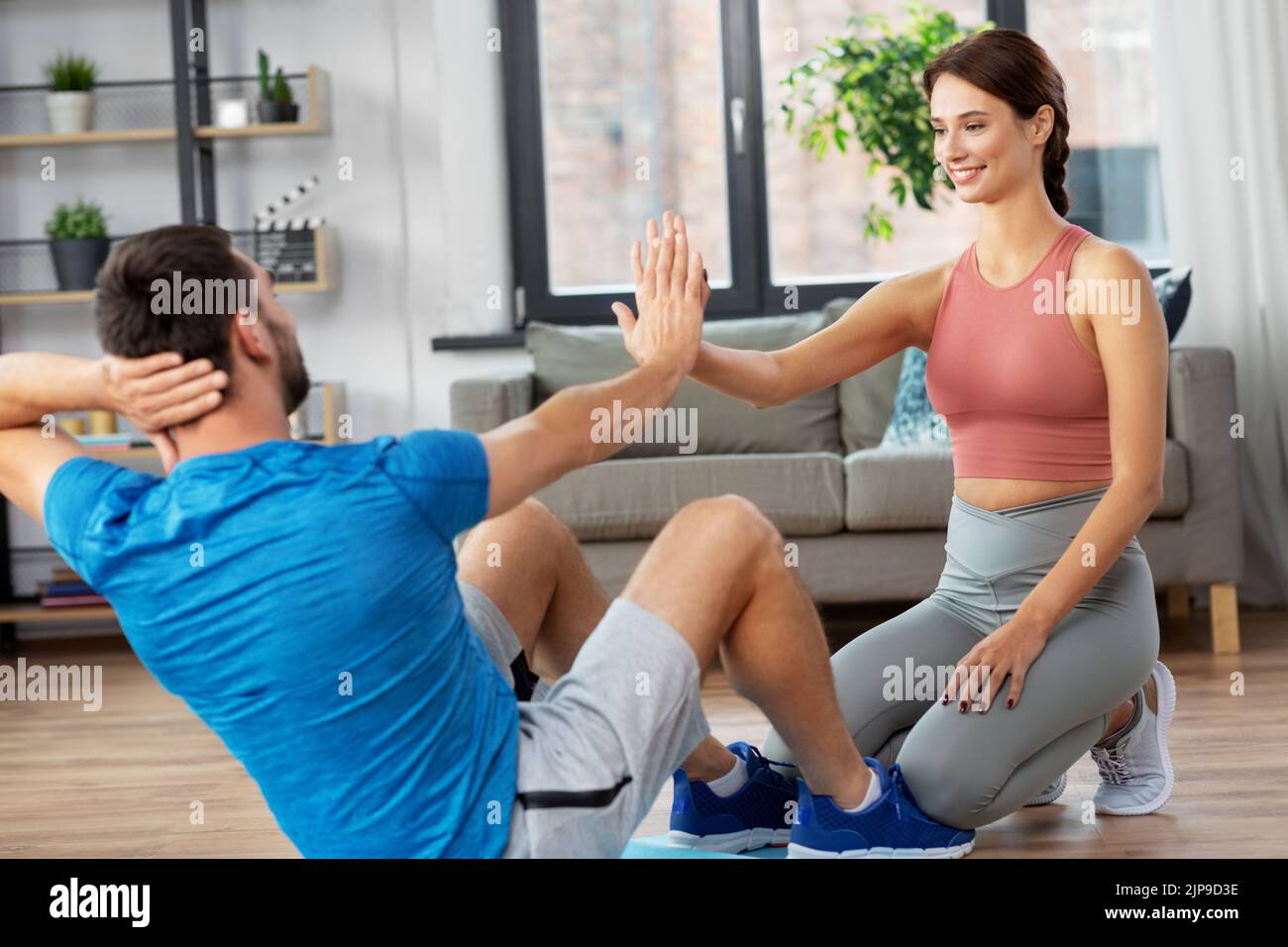 man with personal trainer doing sit ups at home Stock Photo