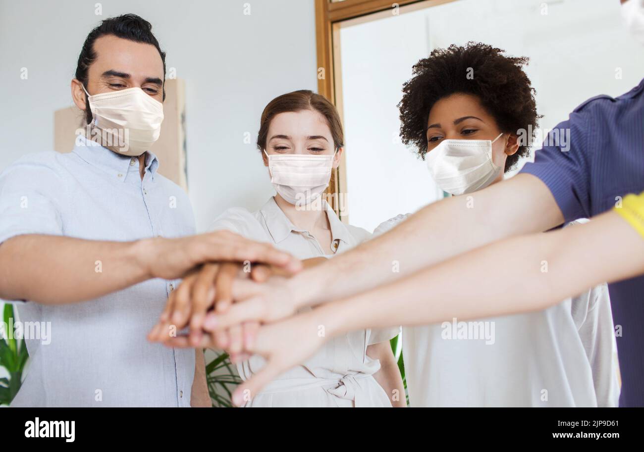 people in masks stacking hands at office Stock Photo - Alamy