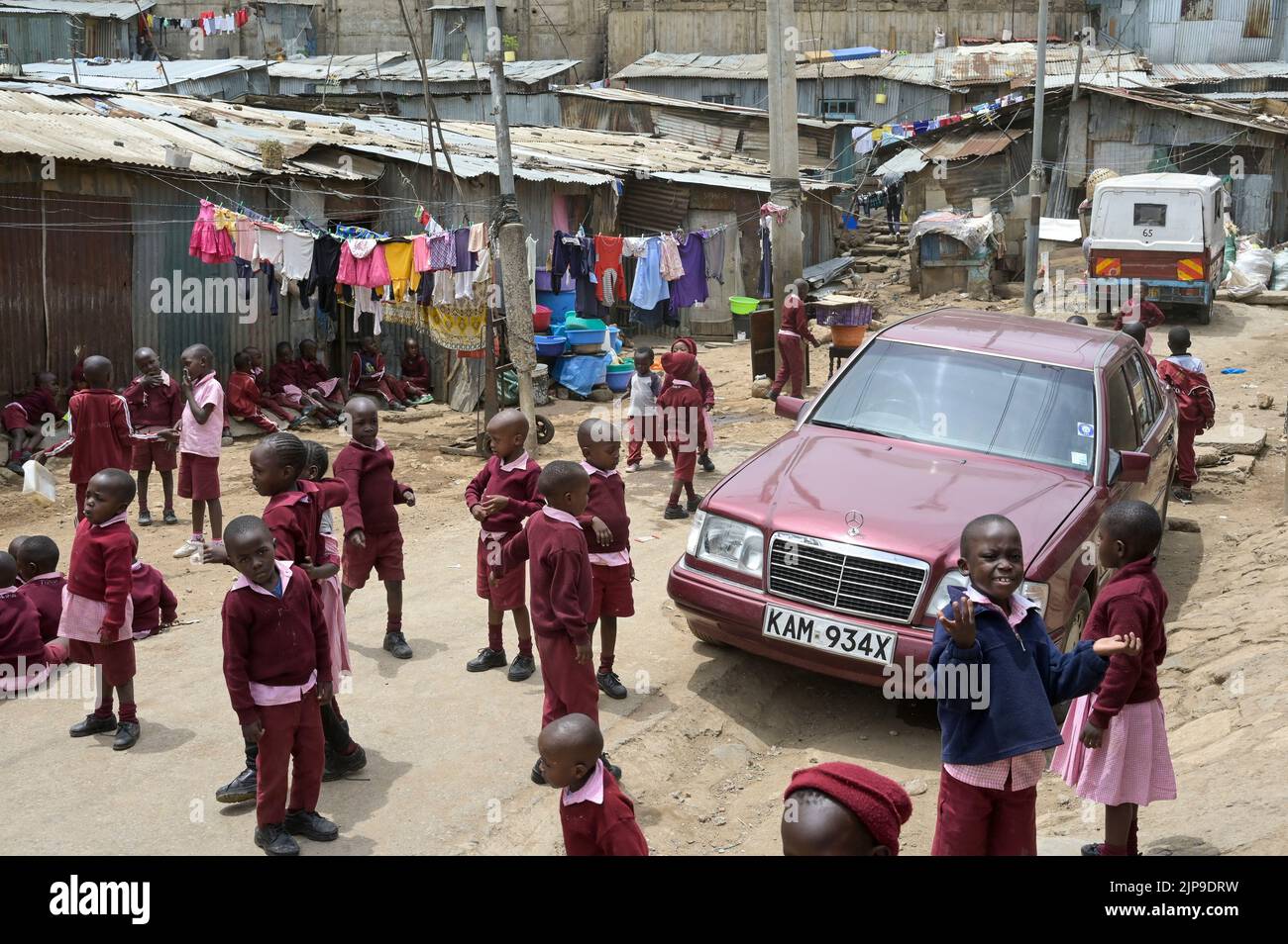 KENYA, Nairobi, Mathare Slum, contrast school children and used Mercedes Benz car from Europe / KENIA, Nairobi, Stadtteil Mathare, Slum, Kontrast Schulkinder und gebrauchter Mercedes Benz aus Europa Stock Photo