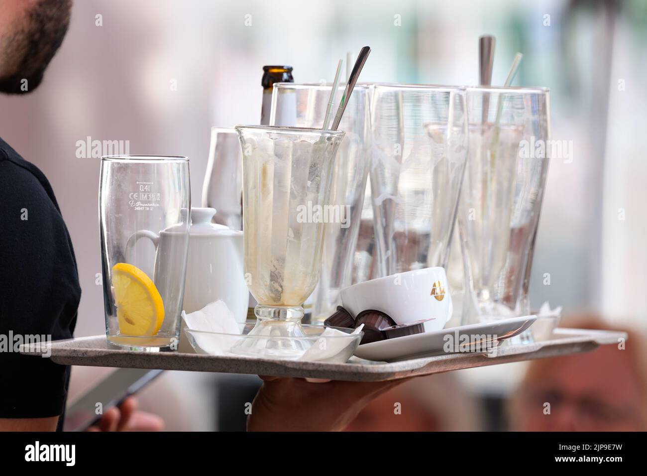 Hamburg, Germany. 16th Aug, 2022. A waiter at the Alsterarkaden carries a tray with used glasses and empty bottles. Credit: Jonas Walzberg/dpa/Alamy Live News Stock Photo