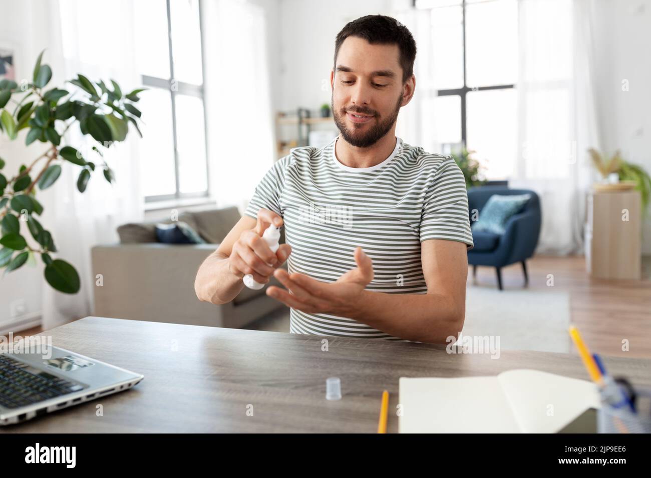 man using hand sanitizer at home office Stock Photo