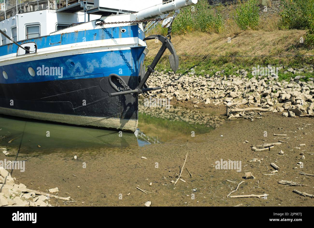 grounded ship in a basin due to low water level of rhine river in germany.Water shortage, drought, climate change and global warming concept. Stock Photo