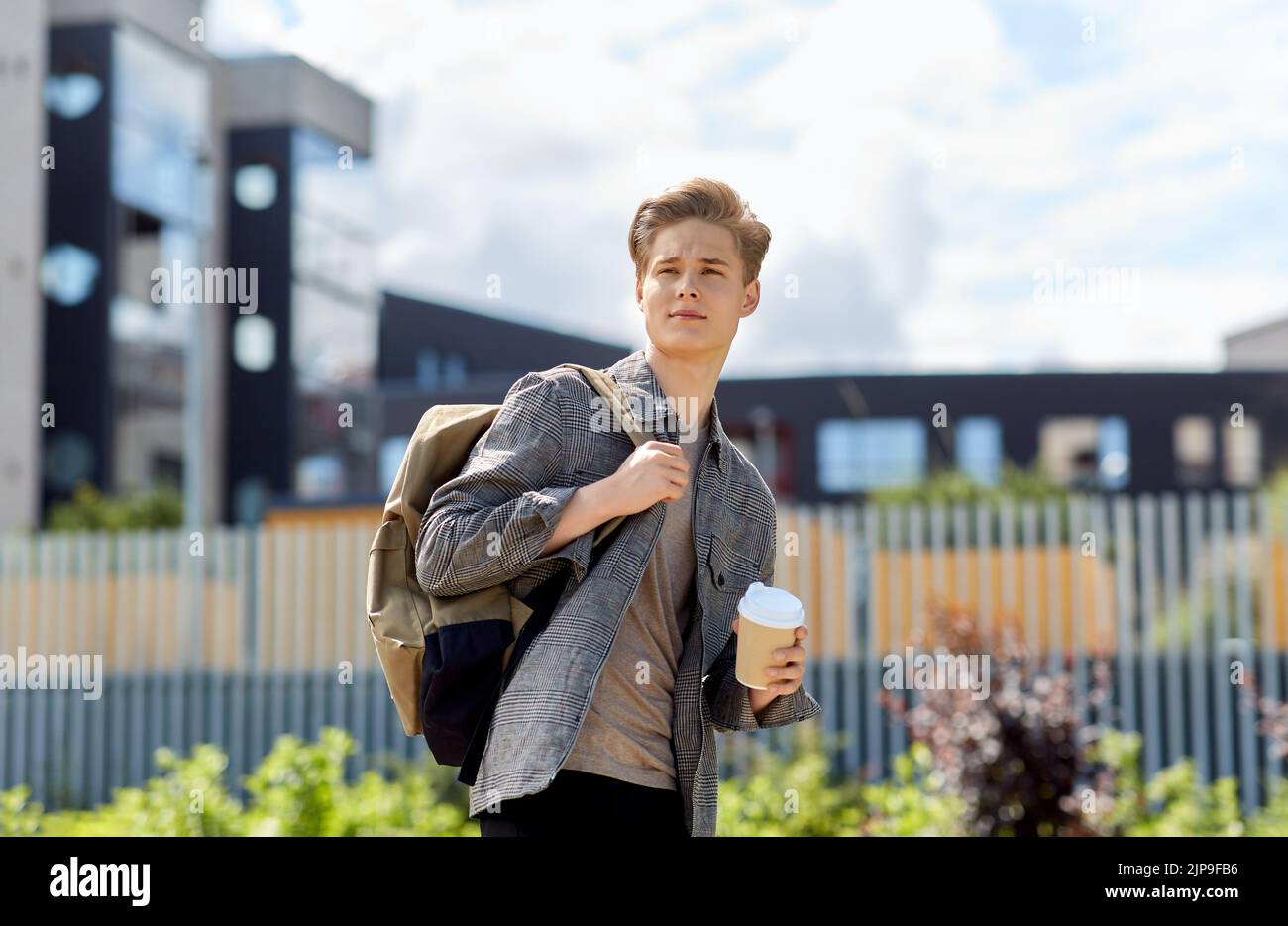 young man with backpack drinking coffee in city Stock Photo