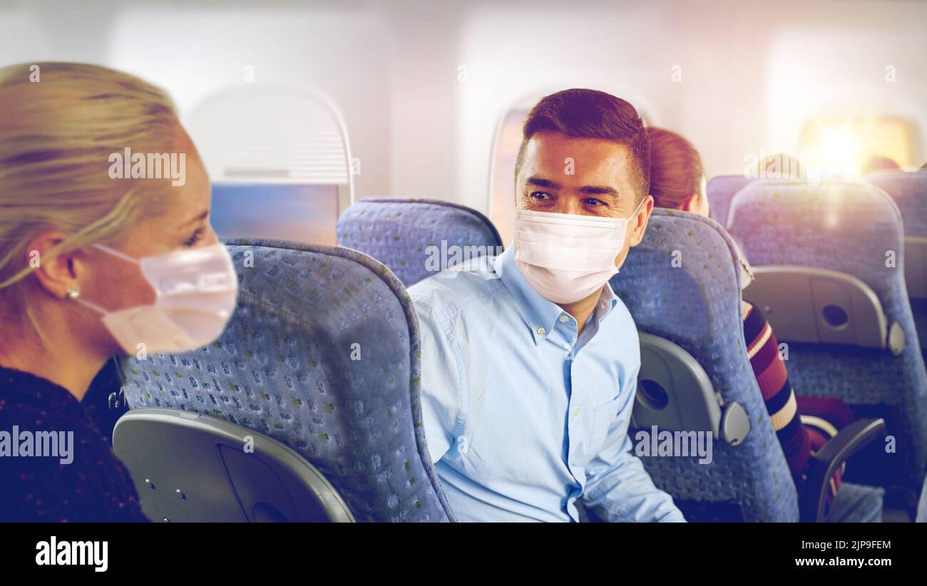 passengers in masks talking in plane Stock Photo
