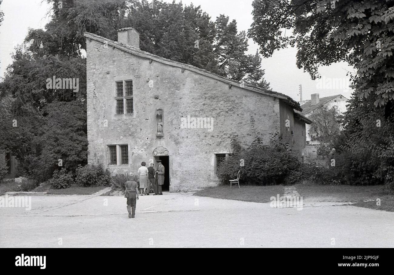 1950s, historical, exterior, La Maison Natale de Jeanne d'Arc, a two-storey stone farm building, with sloping roof, where Joan of Arc was born in the 15th century, Domremy-la-Pucelle, France. A statue stands in front of the house. Her birth house in Domrémy was preserved and became a museum. Also known as the 'The Maid of Orleans' this simple peasant girl is considered a national heroine in French culture, as believing that she was acting under the will of god, she led the French army to victory at Orleans in 1429 against the English during the Hundred Years War. Stock Photo