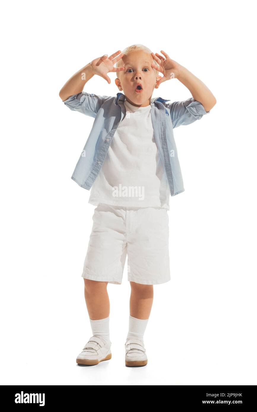 Portrait of little boy, child in casual outfit posing isolated over white studio background. Making faces Stock Photo
