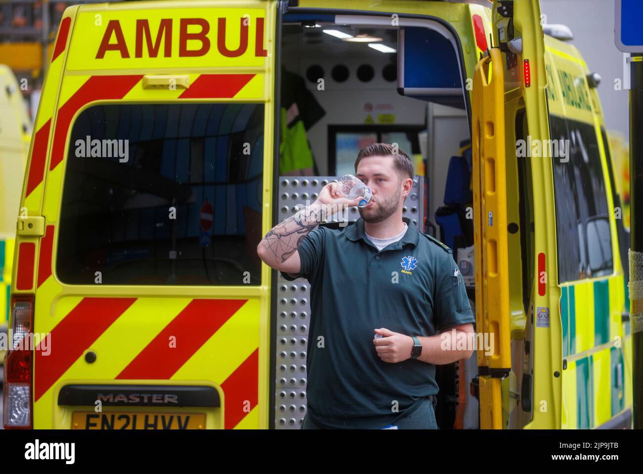 An ambulance worker takes a break during a shift during the hot summer weather. The ambulance service is under pressure with increased workload. Stock Photo