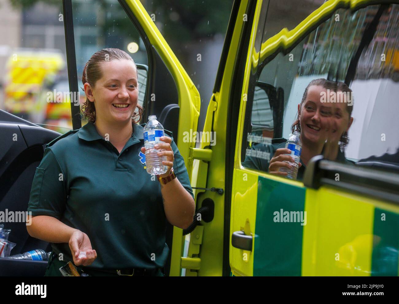 An ambulance worker takes a break during a shift during the hot summer weather. The ambulance service is under pressure with increased workload. Stock Photo