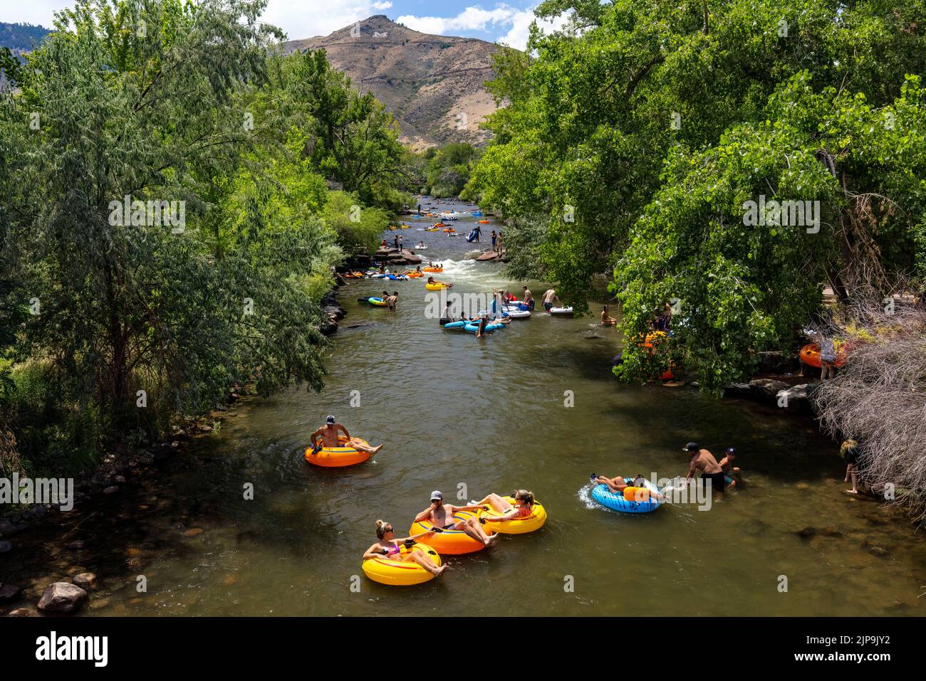 People having fun tubing down Clear Creek in summer. Golden, Colorado, USA Stock Photo