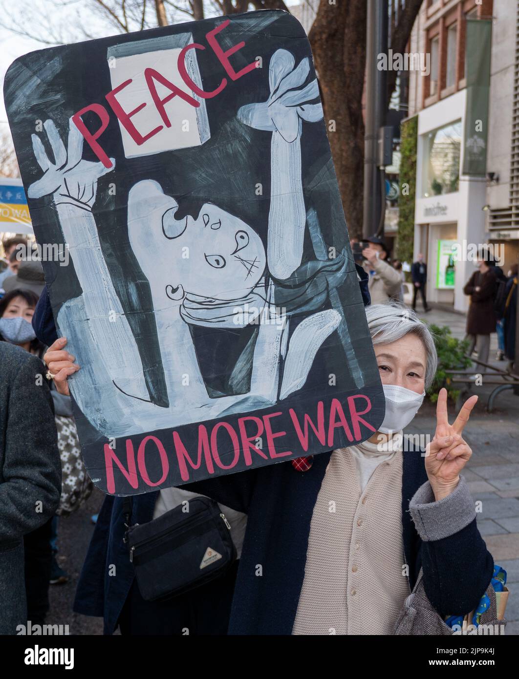 An older woman holds a peace sign to protest the Ukraine-Russia war during a march in Tokyo, Japan. Stock Photo