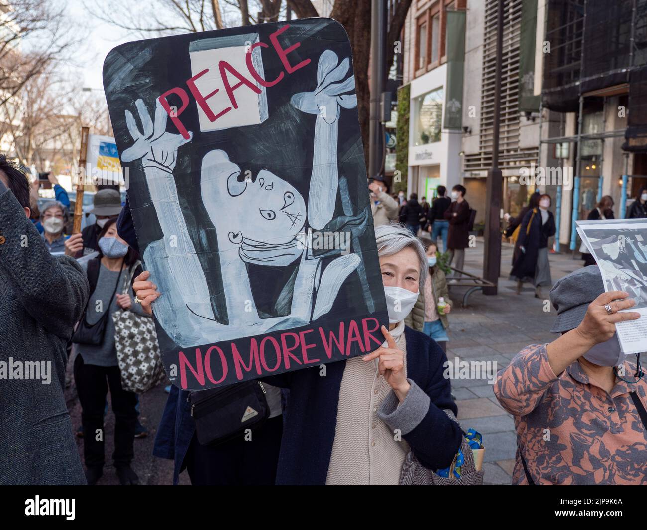 An older woman holds a peace sign to protest the Ukraine-Russia war during a march in Tokyo, Japan. Stock Photo