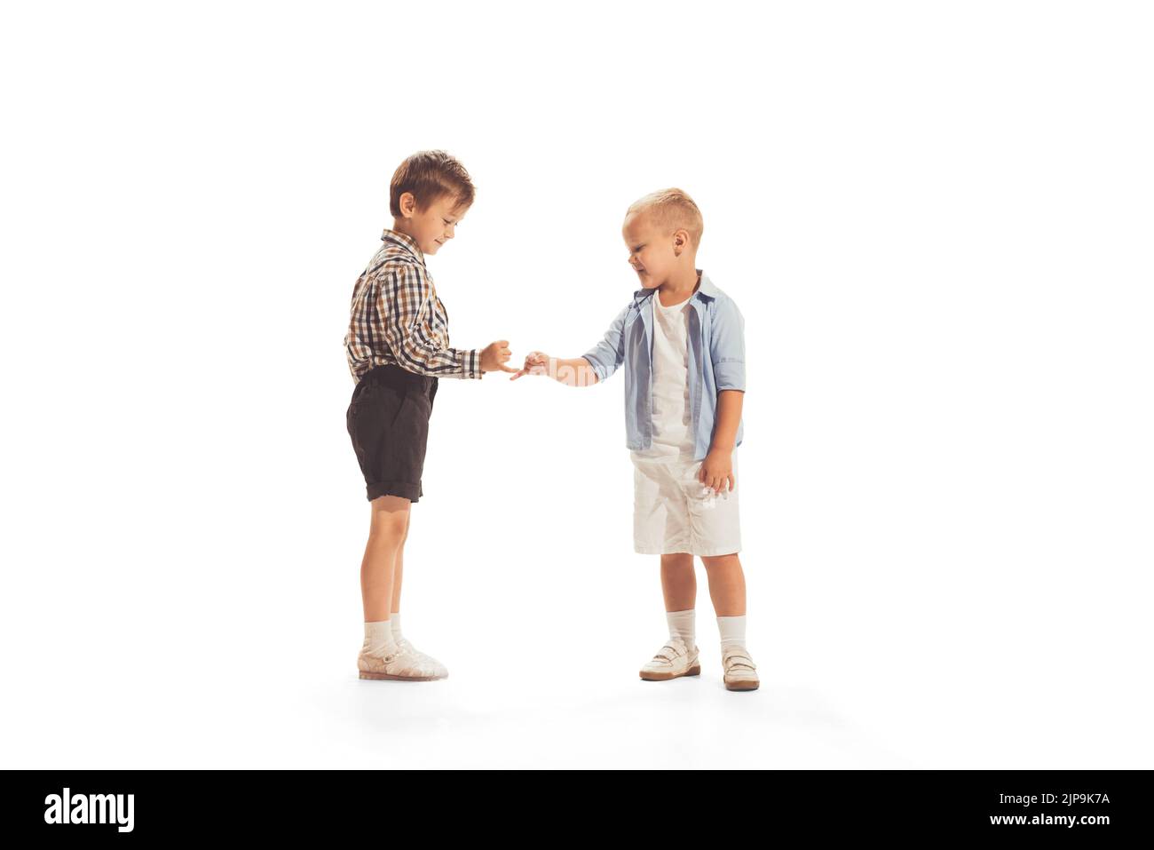 Portrait of two little boys, children playing together, making peace with fingers isolated over white studio background Stock Photo