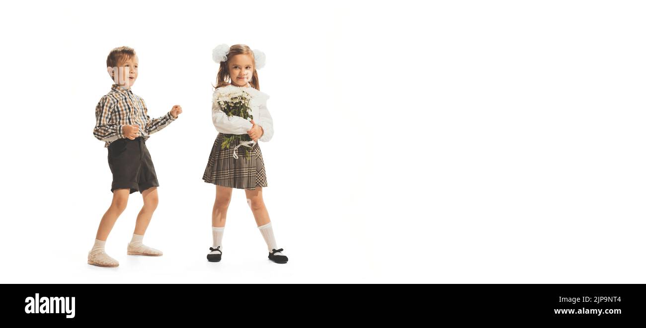 Portrait of children, boy in checkered shirt and girl with flowers posing isolated over white studio background Stock Photo