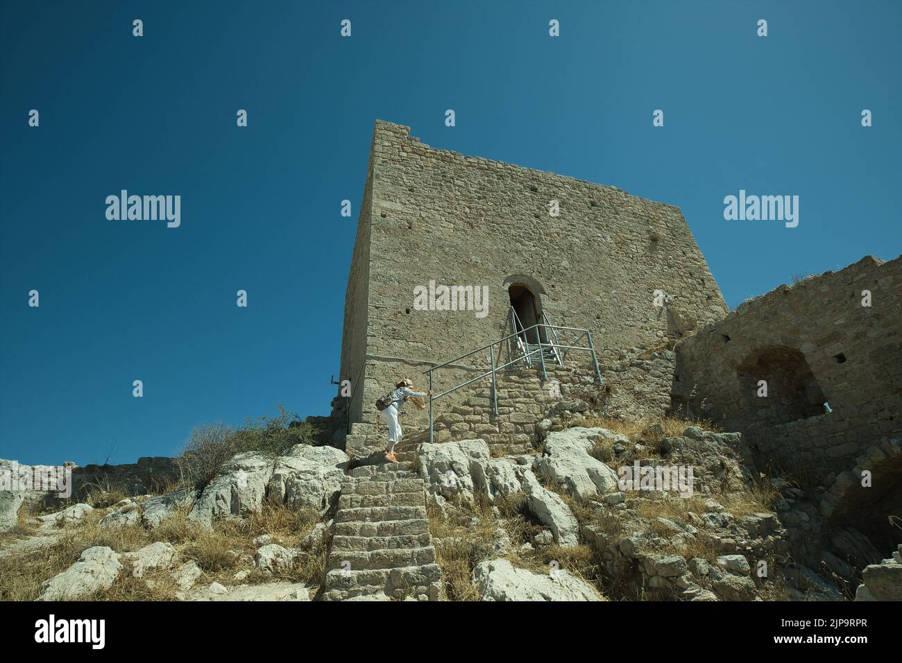 Female tourist entering the Frankish tower in the Acrocorinth site in Corinth, Greece in summer Stock Photo