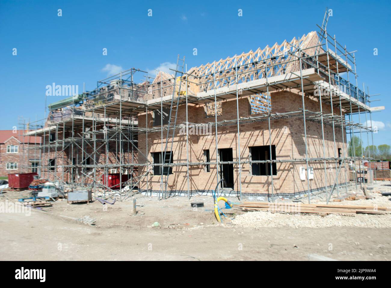 Partially constructed house surrounded by scaffolding on building site Stock Photo