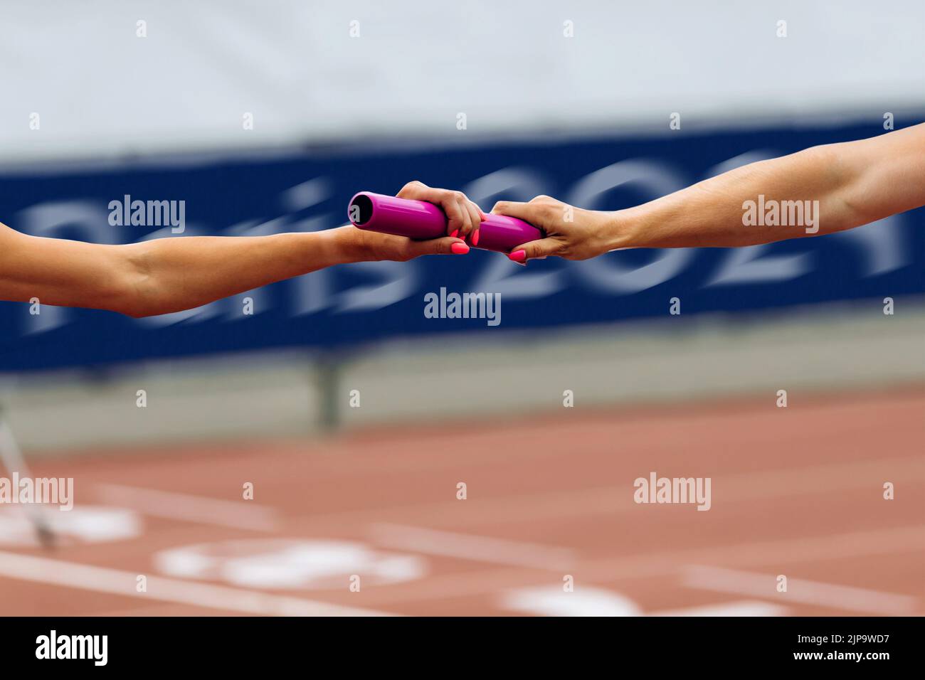 women relay race competition on background Paris 2024 banner Stock