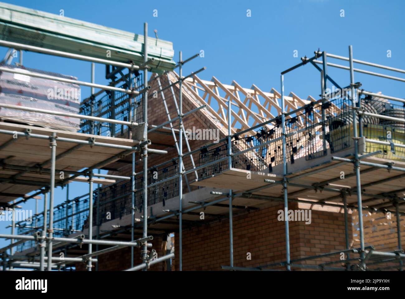Partially constructed house surrounded by scaffolding on building site Stock Photo