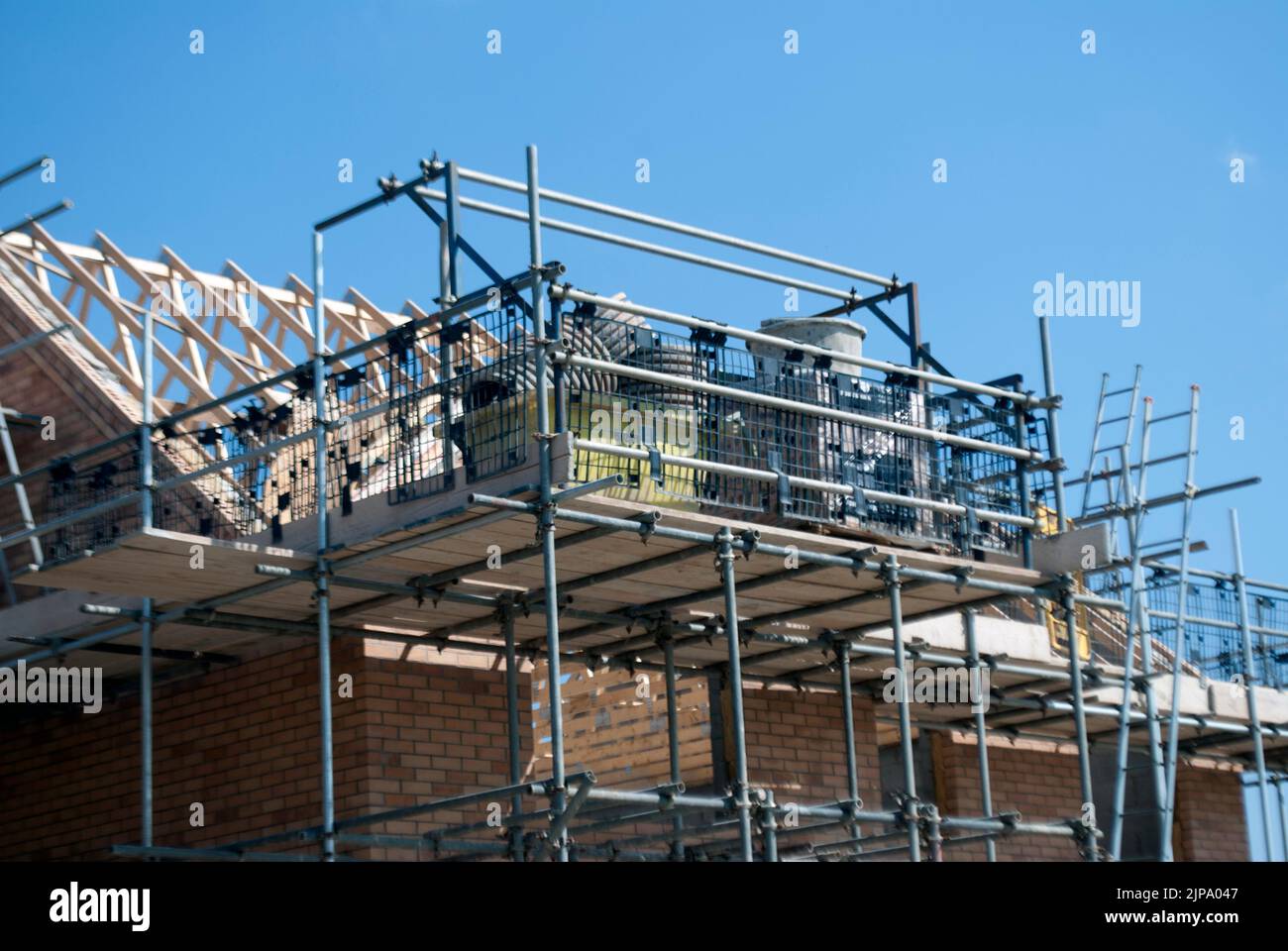 Roof of partially constructed house surrounded by scaffolding on building site Stock Photo